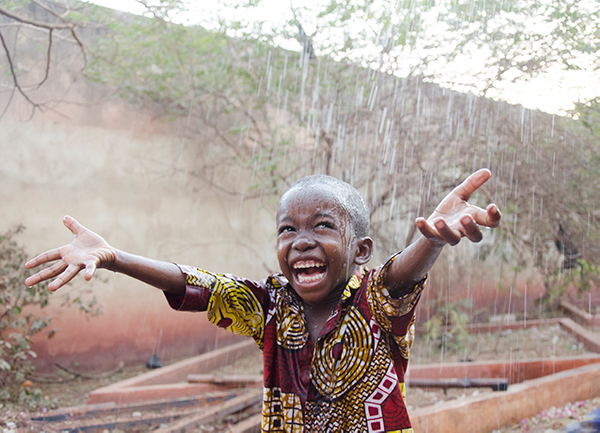 Happy boy plays outside in the rain
