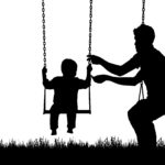 Child playing with dad on a swing silhouette